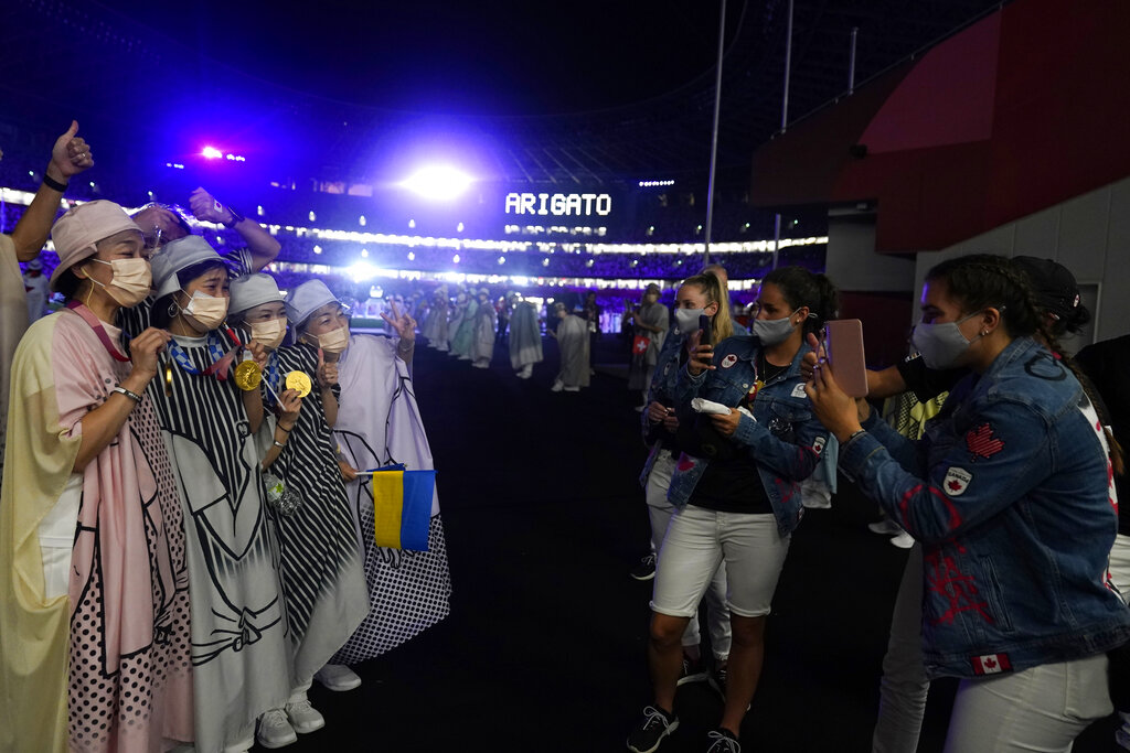 Canadian athletes take pictures of performers with their medals during the closing ceremony in the Olympic Stadium at the 2020 Summer Olympics, Sunday, Aug. 8, 2021, in Tokyo, Japan. (AP Photo/David Goldman)