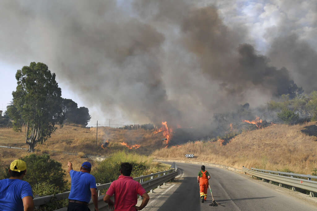Volunteers try to control fire in the Municipality of Blufi, in the upper Madonie, near Palermo, Sicily, Italy, as  many wildfires continue plaguing the region. Sicily, Sardinia, Calabria and also central Italy, where temperatures are expected to reach record hights, were badly hit by wildfires. Climate scientists say there is little doubt that climate change from the burning of coal, oil and natural gas is driving extreme events, such as heat waves, droughts, wildfires, floods and storms. (AP Photo/Salvatore Cavalli)