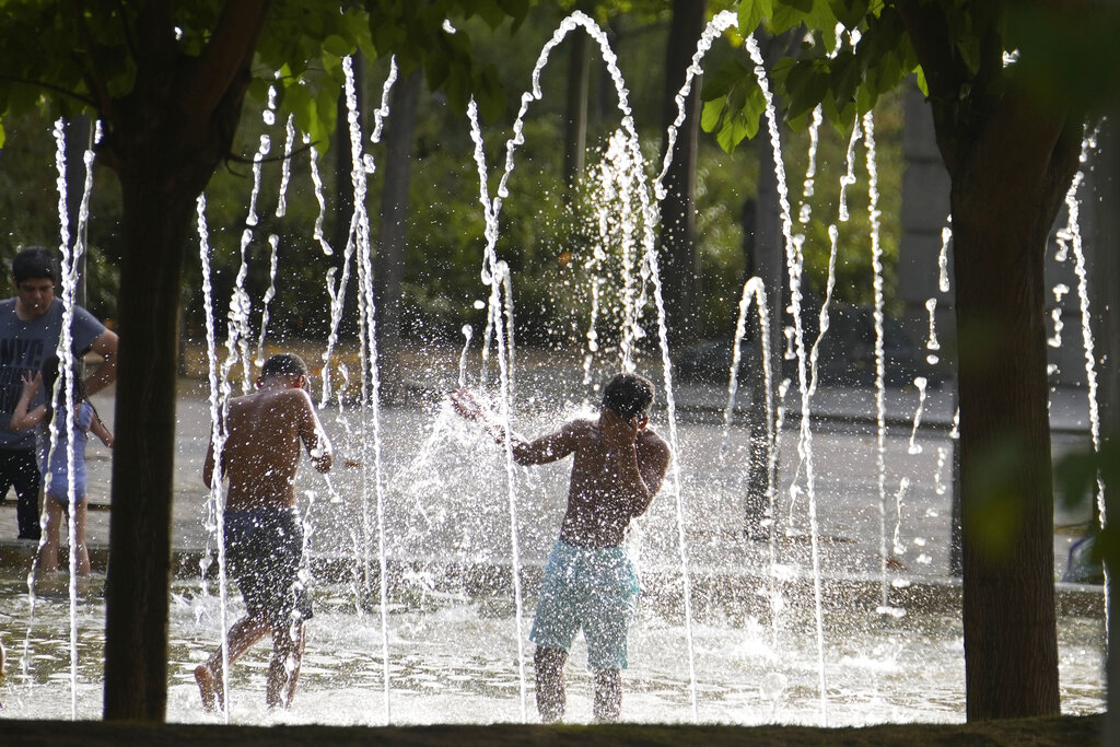 People try to keep cool in a fountain in Madrid, Spain, Wednesday, Aug. 11, 2021. Madrid registered around 38 degrees Celsius (100.4 fahrenheit) Wednesday as Spain and Portugal brace for temperatures above 40 degrees Celsius (104 degrees Fahrenheit) in coming days, as a mass of hot, dry air from Africa moves north into the Iberian peninsula. (AP Photo/Paul White)