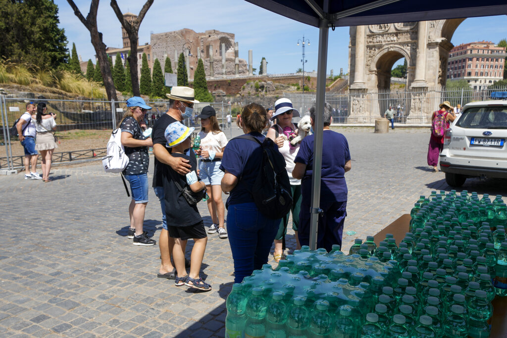 Civil protection volunteers distribute free bottles of water to tourists next to the Colosseum, in Rome, Thursday, Aug. 12, 2021. In Italy, 15 cities received warnings from the health ministry about high temperatures and humidity with peaks predicted for Friday. The cities included Rome, Florence and Palermo, but also Bolzano, which is usually a refreshing hot-weather escape in the Alps, (AP Photo/Andrew Medichini)