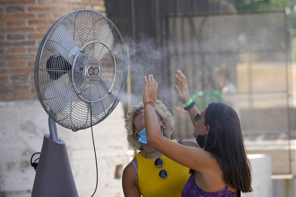 A woman refreshes at a fan nebulizing water next to the Colosseum, in Rome, Thursday, Aug. 12, 2021. In Italy, 15 cities received warnings from the health ministry about high temperatures and humidity with peaks predicted for Friday. The cities included Rome, Florence and Palermo, but also Bolzano, which is usually a refreshing hot-weather escape in the Alps, (AP Photo/Andrew Medichini)