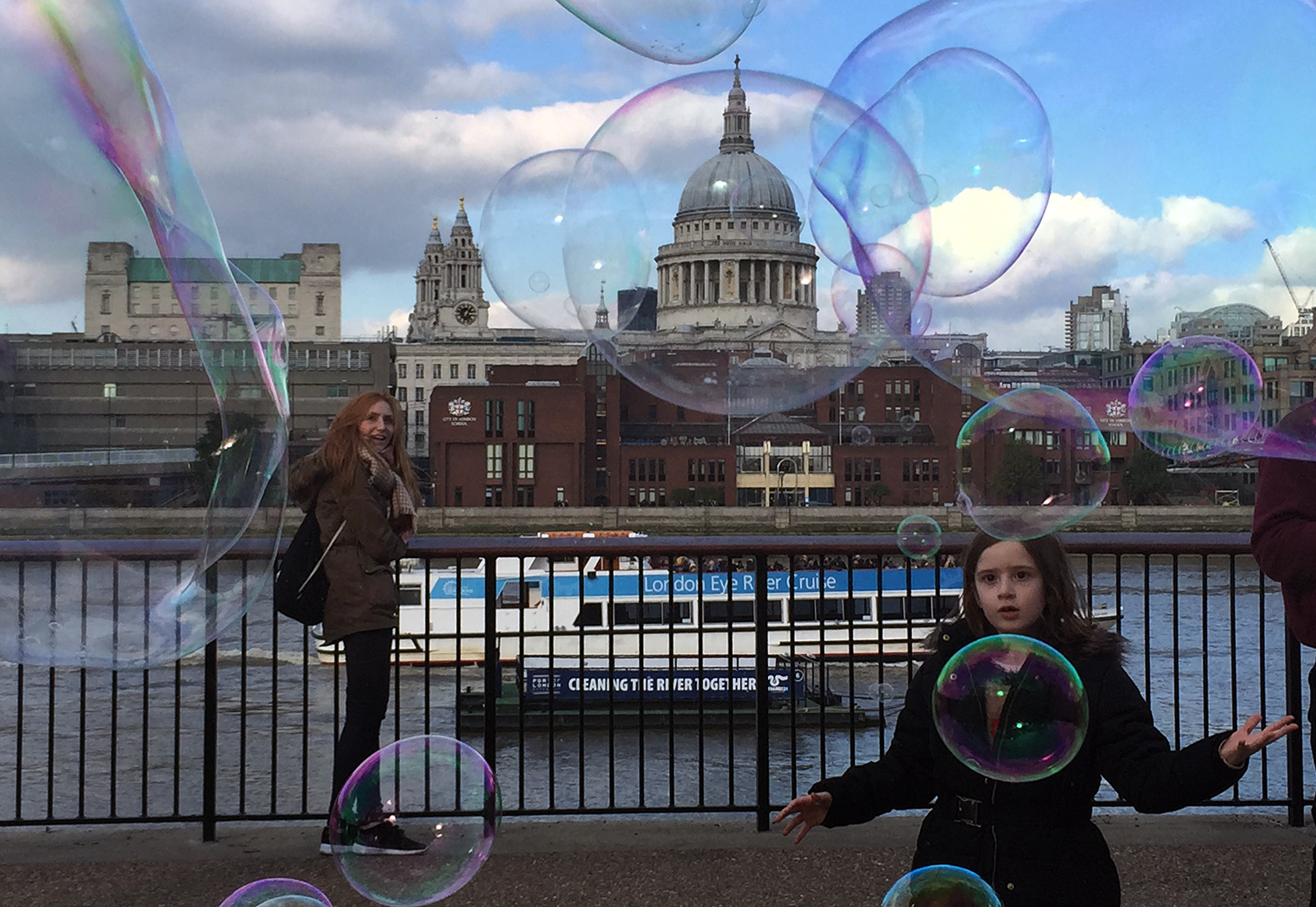 Tourists watch soap bubbles along the Thames river, London, backdropped by St. Paul's Cathedral, Tuesday, Oct. 20, 2015. (AP Photo/Christophe Ena)