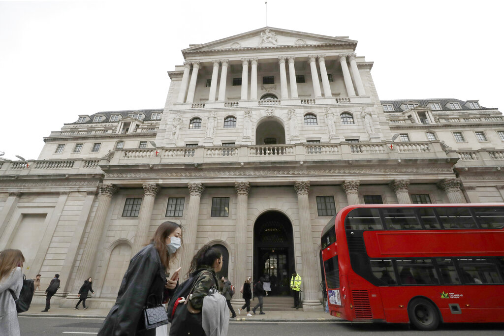 FILE - In this Wednesday, March 11, 2020 file photo, pedestrians wearing face masks pass the Bank of England in London.  The U.K. economy has officially fallen into a recession after official figures showed it contracting by a record 20.4% in the second quarter as a result of lockdown measures put in place to counter the coronavirus pandemic. The slump recorded by the Office for National Statistics follows a 2.2% quarterly contraction in the first three months of the year. ( (AP Photo/Matt Dunham, File)