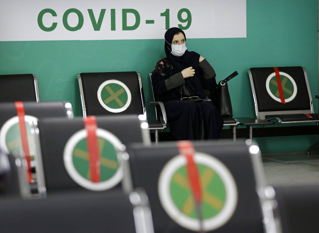 A woman waits to receive her first dose of the Pfizer coronavirus vaccine at a vaccination center, at the old Jiddah airport, Saudi Arabia, Tuesday, May 18, 2021. (AP Photo/Amr Nabil)