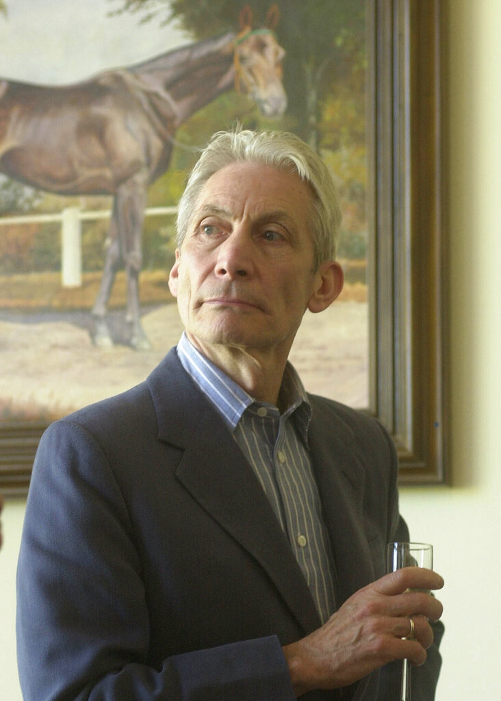FILE - The Rolling Stones drummer and horse breeder Charlie Watts toasts with champagne after his horse won a race at the Sluzewiec horse racing track in Warsaw on May 25, 2002. Watts' publicist, Bernard Doherty, said Watts passed away peacefully in a London hospital surrounded by his family on Tuesday, Aug. 24, 2021. He was 80.  (AP Photo/Alik Keplicz, File)