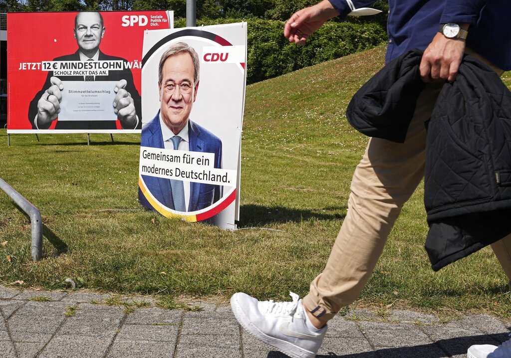 A election poster for the German Social Democrats, SPD, shows top candidate Olaf Scholz, left, behind a poster for top candidate for the German Christian Democrats, CDU, Armin Laschet, right, at a street in Duesseldorf, Germany, Wednesday, Aug. 25, 2021. A large chunk of the German electorate remains undecided going into an election that will determine who succeeds Angela Merkel as chancellor after 16 years in power. Recent surveys show that support for German political parties has flattened out, with none forecast to receive more than a quarter of the vote. (AP Photo/Martin Meissner)
