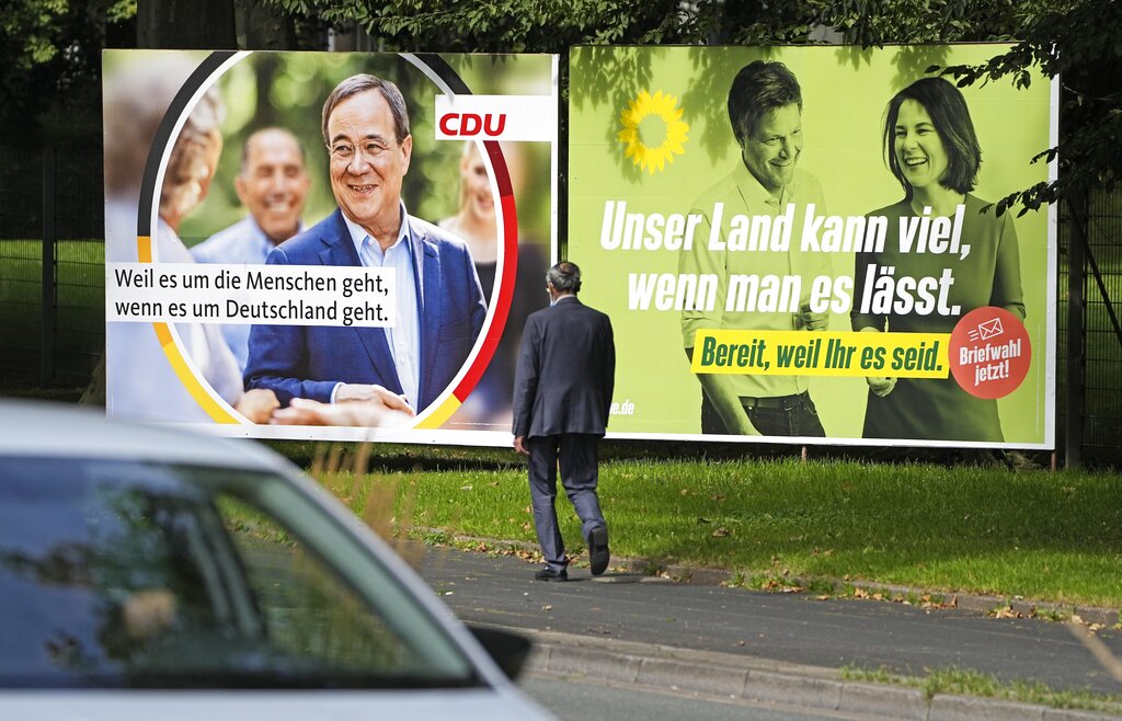 A election poster for the Green Party shows top candidate Annalena Baerbock, right, beside a poster for top candidate for the German Christian Democrats, Armin Laschet, left, at a street in Essen, Germany, Wednesday, Aug. 25, 2021. A large chunk of the German electorate remains undecided going into an election that will determine who succeeds Angela Merkel as chancellor after 16 years in power. Recent surveys show that support for German political parties has flattened out, with none forecast to receive more than a quarter of the vote. (AP Photo/Martin Meissner)