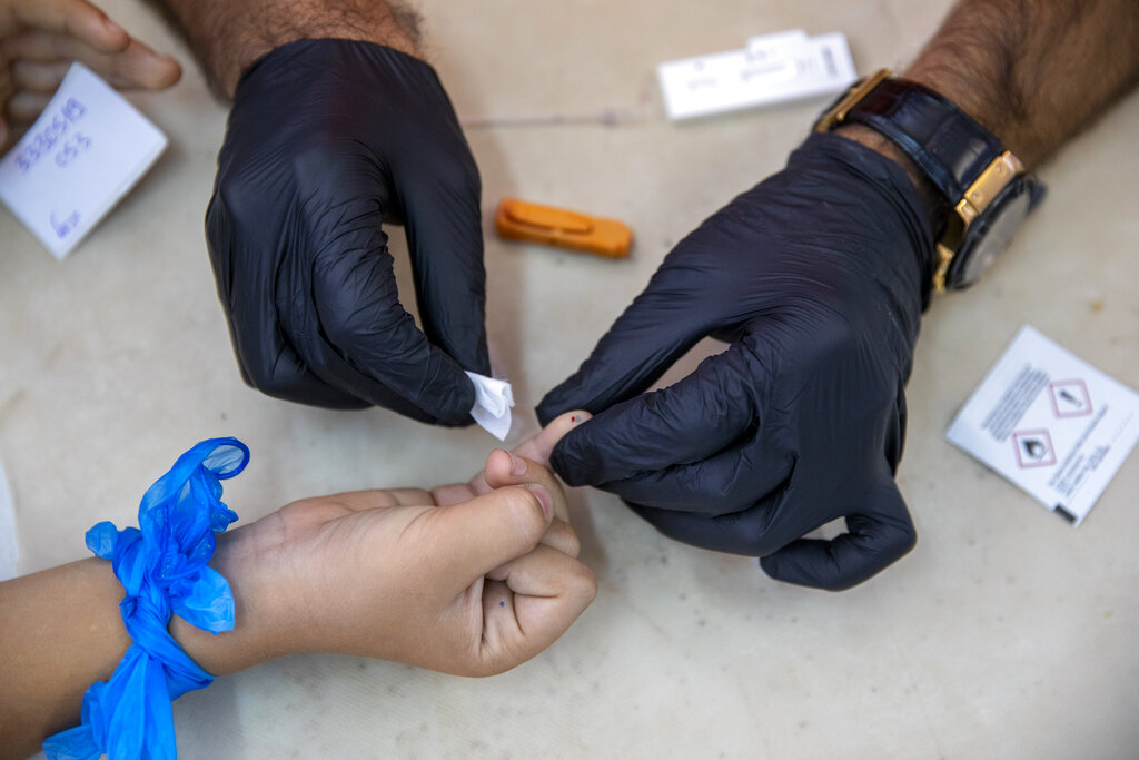 An Israeli soldier conducts a COVID-19 antibody test on a child in Hadera, Israel, Monday, Aug. 23, 2021. Ahead of the opening of the school year on Sept. 1, the Israeli army's Home Front Command is conducting serology tests on children age 3-12 who have not yet tested positive for coronavirus and are not yet listed as recovered, to see if they have antibodies. If a child tests positive for coronavirus antibodies, they can be issued a 