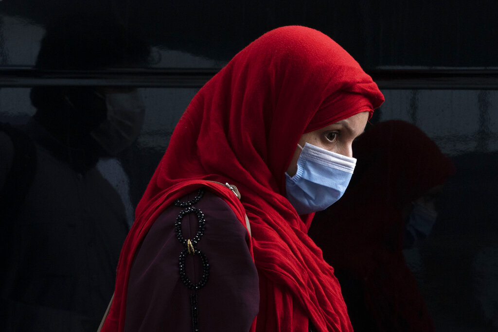 A woman evacuated from Kabul, Afghanistan, walks through the terminal before boarding a bus after they arrived at Washington Dulles International Airport, in Chantilly, Va., on Monday, Aug. 30, 2021. (AP Photo/Jose Luis Magana)
