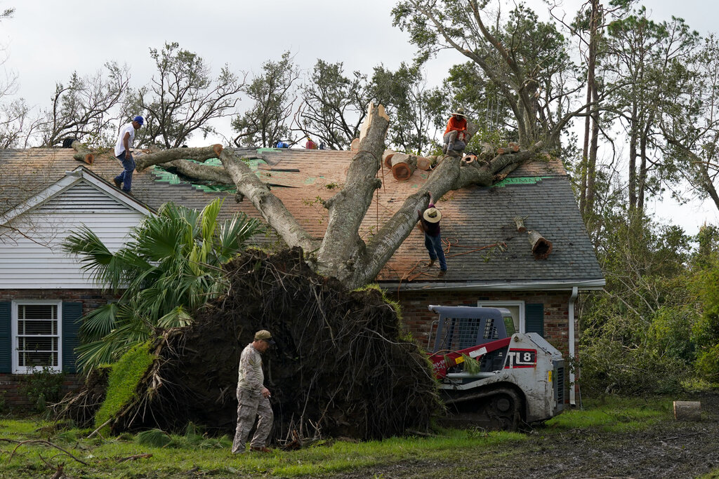 Workers remove a tree that toppled over onto the roof of a home Tuesday, Aug. 31, 2021, in Houma, La., in the aftermath of Hurricane Ida. (AP Photo/David J. Phillip)