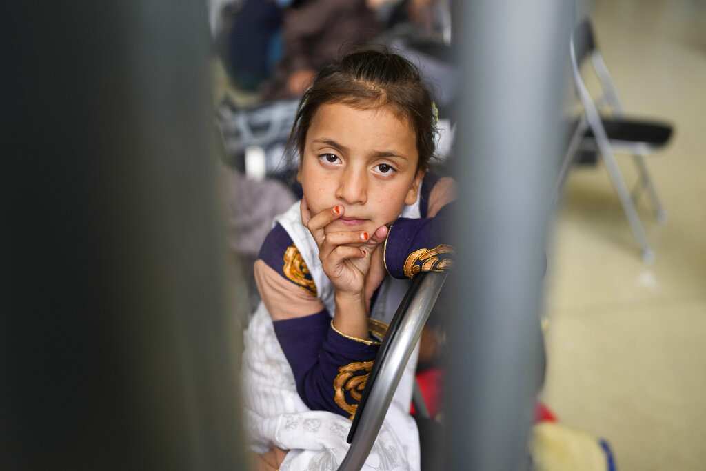 A girl from Afghanistan waits with other evacuees to fly to the United States or another safe location in a makeshift departure gate inside a hanger at the U.S. Air Base in Ramstein, Germany, Wednesday, Sept. 1, 2021. The United States is using the military base in Ramstein, Palatinate, as a hub for the evacuation of shelter seekers and local forces from Afghanistan. (AP Photo/Markus Schreiber)