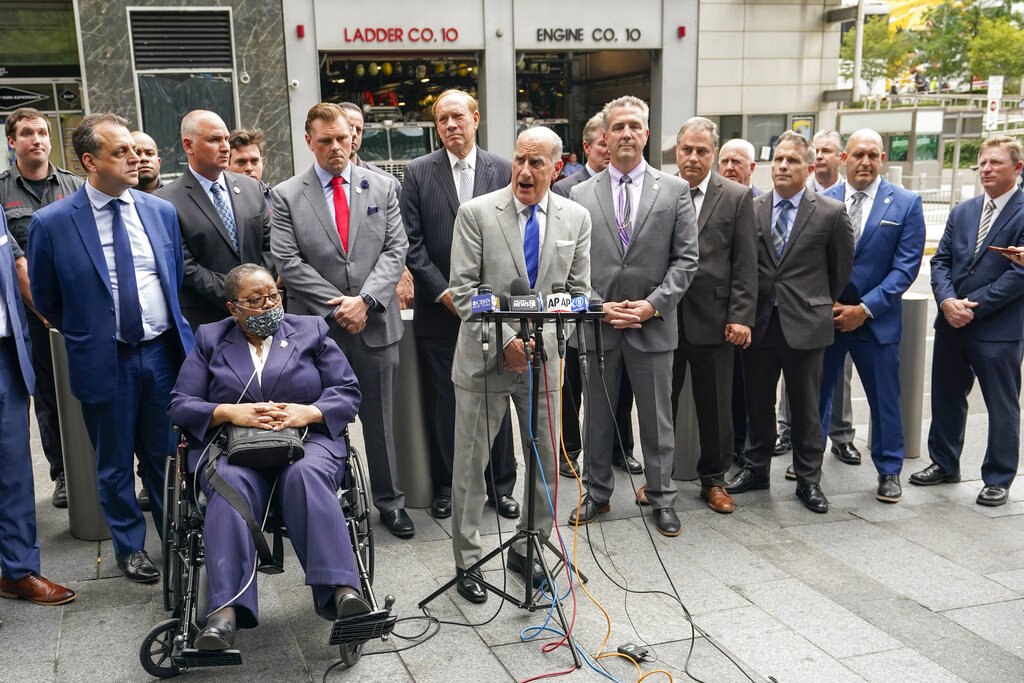 Retired NYPD Detective Barbara Burnette, foreground left, who worked on the World Trade Center pile for 23 days after the terrorist attacks in 2001 is joined by her attorney Nicholas Papain, center, and former New York Gov. George Pataki, background center, and other 9/11 first responders during a news conference, Wednesday, Sept. 8, 2021, in New York.  Two decades after the collapse of the World Trade Center, people are still coming forward to report illnesses that might be related to toxic dust that billowed over the city after the terror attack. (AP Photo/Mary Altaffer)