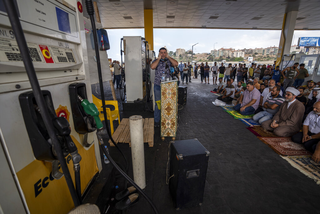 A man calls for prayer as dozens of people held Friday prayers at a gas station to protest severe fuel shortages that Lebanon has been witnessing for weeks, in the coastal town of Jiyeh, south of Beirut, Lebanon, Friday, Sept. 3, 2021.  Outside the gas station, a line of cars stretched on for about five kilometers (about 3 miles), blocking the road. (AP Photo/ Hassan Ammar)
