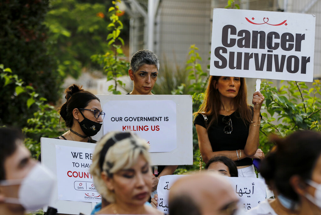 FILE - In this Aug. 26, 2021 file photo, cancer patients and supporters hold placards during a sit-in to protest shortages in medications, in front of the U.N. headquarters in Beirut, Lebanon. Amid a devastating economic crisis, Lebanon is grappling with severe shortages of medical supplies, fuel and other necessities, threatening treatment for tens of thousands of people. (AP Photo/Bilal Hussein, File)