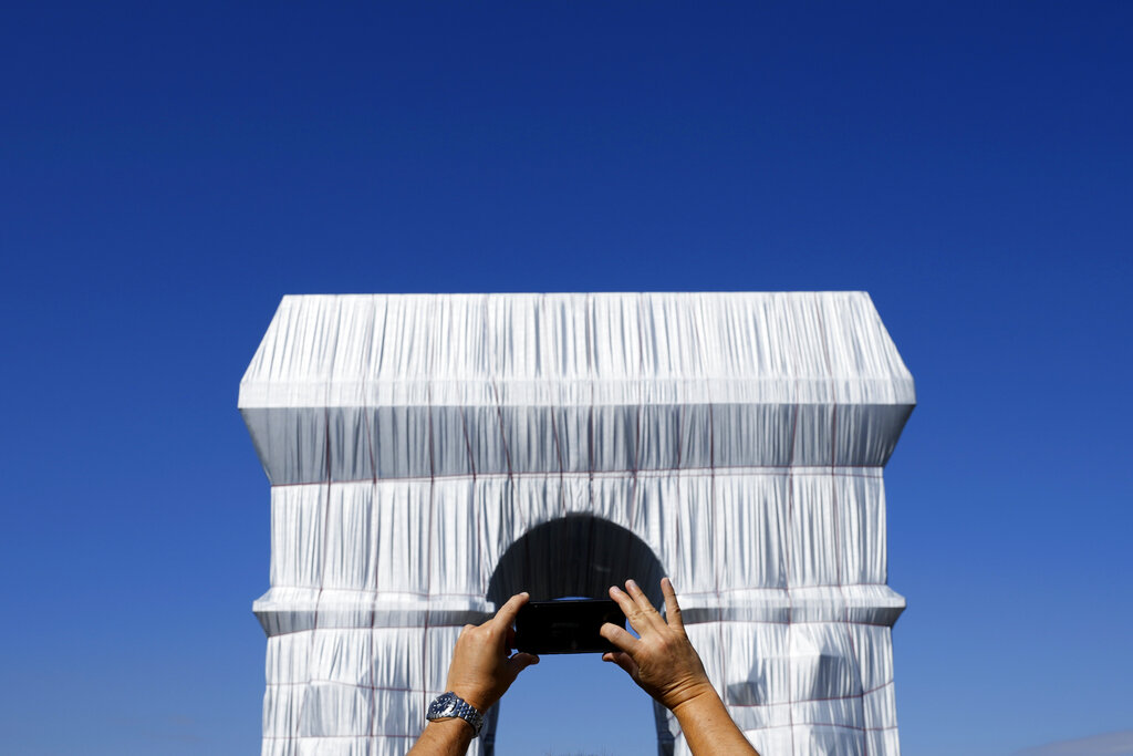 A man pictures the wrapped Arc de Triomphe monument Saturday, Sept. 18, 2021 in Paris. The 
