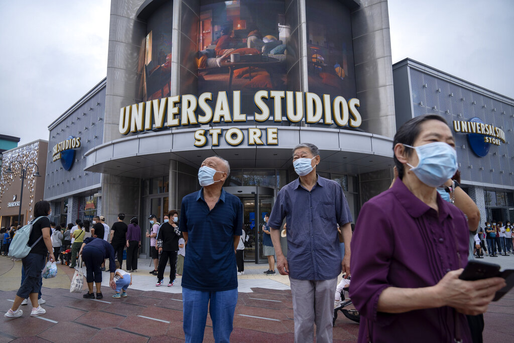 People wearing face masks to help protect against COVID-19 walk past a Universal Studios Store near the entrance to Universal Studios Beijing in Beijing, Saturday, Sept. 4, 2021. The newest location of the global brand of theme parks officially opens on Sept. 20, though an adjacent shopping and entertainment district opened to the public this week. (AP Photo/Mark Schiefelbein)