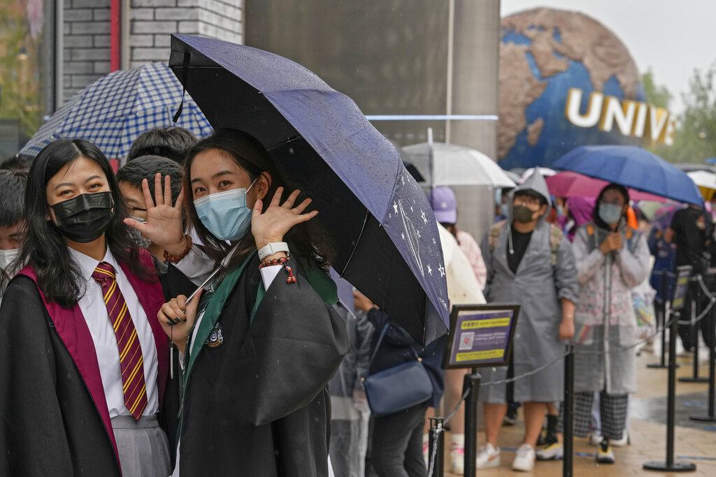 Women wearing face masks to help protect themselves from coronavirus wave as they line-up to enter a merchandise store at the Universal Studios Beijing in Beijing, Monday, Sept. 20, 2021. Thousands of people brave the rain visit to the newest location of the global brand of theme parks which officially opens on Monday. (AP Photo/Andy Wong)