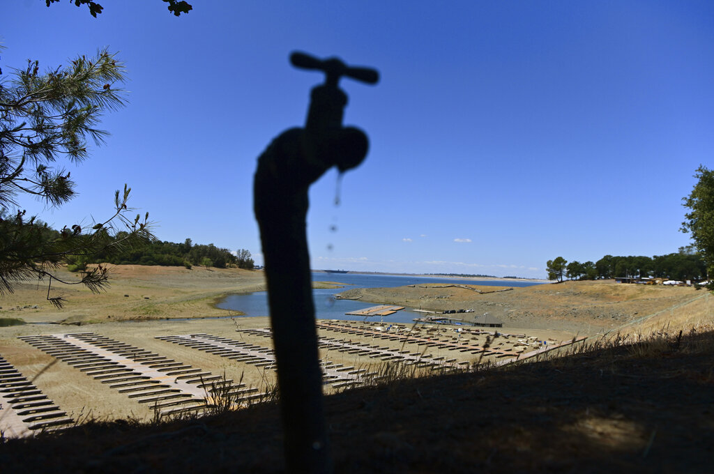 FILE - In this May 22, 2021, file photo, water drips from a faucet near boat docks sitting on dry land at the Browns Ravine Cove area of drought-stricken Folsom Lake, currently at 37% of its normal capacity, in Folsom, Calif. The sweeping $1 trillion infrastructure bill approved by the Senate this week includes funding for Western water projects that farmers, water providers and environmentalists say are badly needed across the parched region. (AP Photo/Josh Edelson, File)
