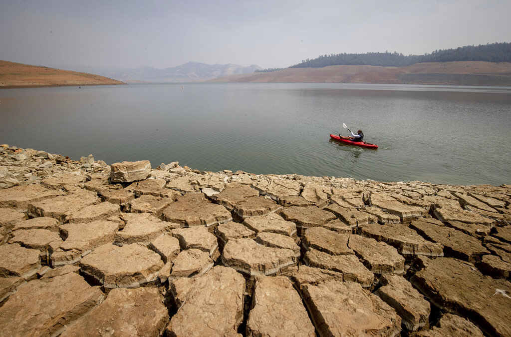 A kayaker paddles in Lake Oroville as water levels remain low due to continuing drought conditions in Oroville, Calif., Sunday, Aug. 22, 2021. (AP Photo/Ethan Swope)