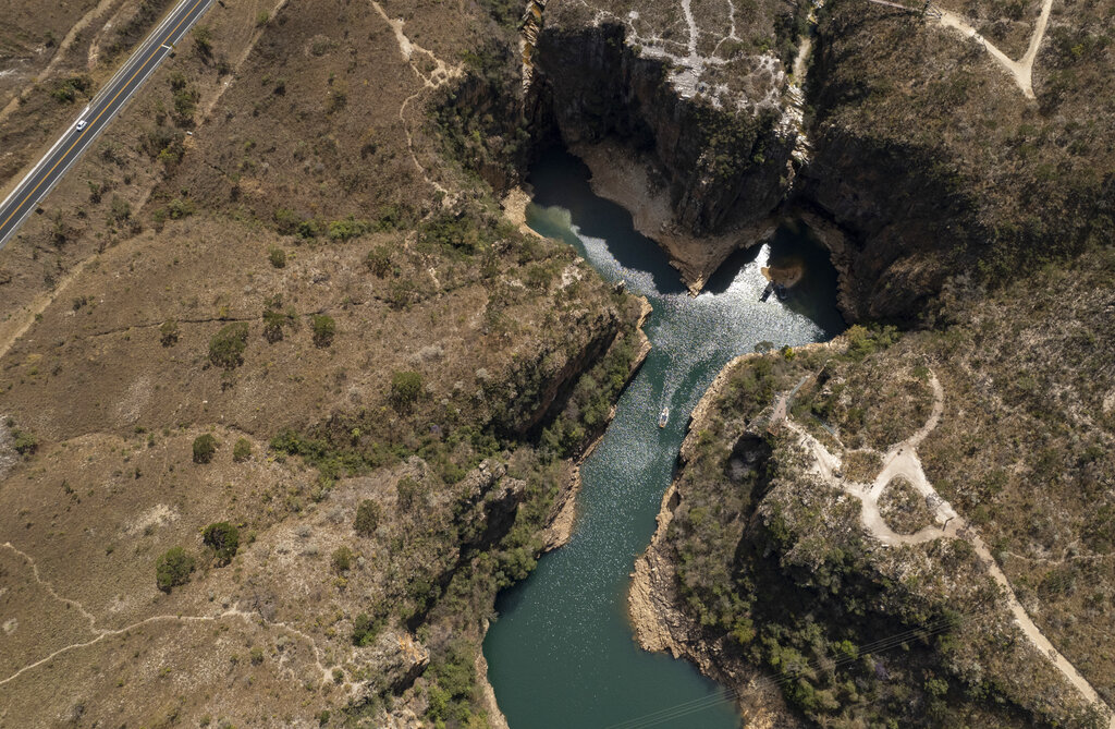 A tourist boat navigates through a canyon at the Furnas reservoir near Sao Jose da Barra, Brazil, Thursday, Sept. 2, 2021. Due to the ongoing drought some reservoirs like the Furnas, are reaching critically low levels, impacting water and energy supply in the country's most populous region. (AP Photo/Andre Penner)