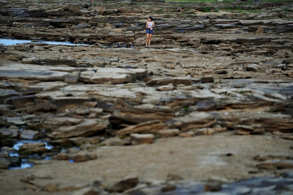 A girl walks on the exposed bed of the Paraguay River, in Villeta, Paraguay, Monday, Sept. 6, 2021, amid an ongoing drought. (AP Photo/Jorge Saenz)