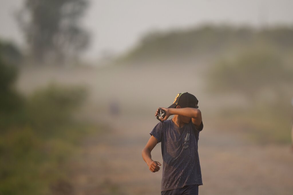A boy covers his face from the dust amid an ongoing drought, in Chaco-i, Paraguay, Monday, Sept. 20, 2021. (AP Photo/Jorge Saenz)