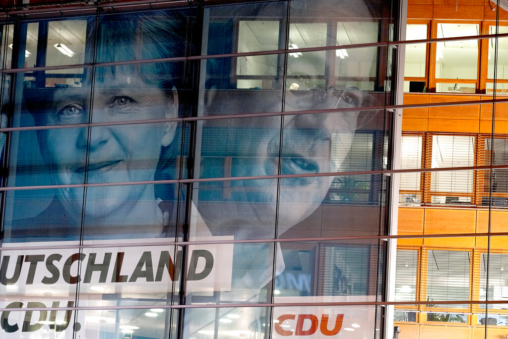 Posters of German Chancellor Angela Merkel and Armin Laschet, the top CDU candidate are placed on the facade of the party headquarters after the German parliament elections in Berlin, Sunday, Sept. 26, 2021. German voters are choosing a new parliament in an election that will determine who succeeds Chancellor Angela Merkel after her 16 years at the helm of Europe's biggest economy.(AP Photo/Markus Schreiber)