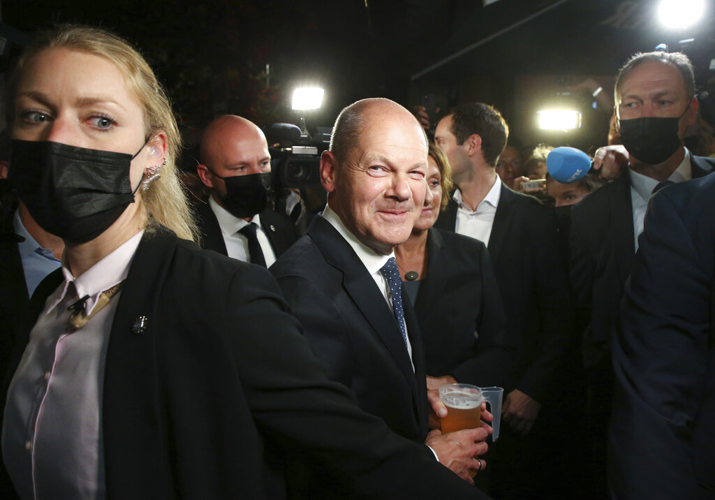 Olaf Scholz, center, Finance Minister and SPD candidate for Chancellor, drinks a beer as he leaves the election party at Willy Brandt House in Berlin, Sunday, Sept. 26, 2021. Exit polls show the center-left Social Democrats in a very close race with outgoing Chancellor Angela Merkel's bloc in Germany's parliamentary election, which will determine who succeeds the longtime leader after 16 years in power. (Wolfgang Kumm/dpa via AP)