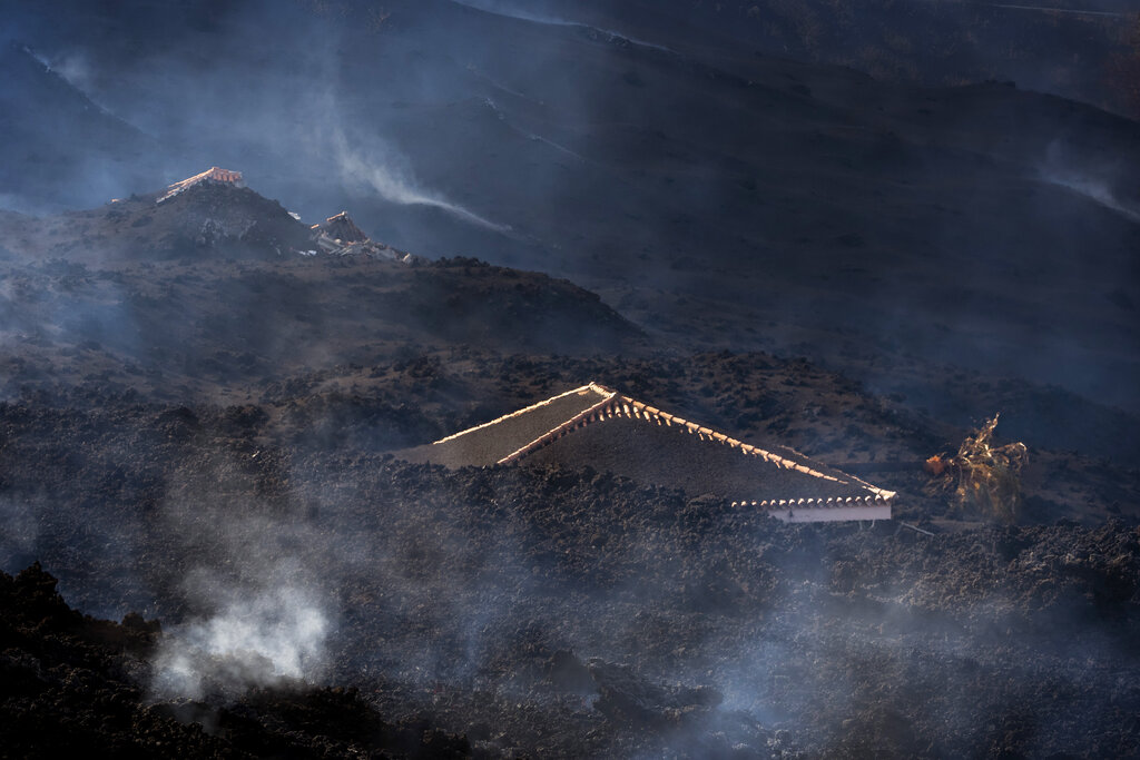 A house is covered in debris after an eruption of a volcano near El Paso on the island of La Palma in the Canaries, Spain, Tuesday, Sept. 21, 2021. A dormant volcano on a small Spanish island in the Atlantic Ocean erupted on Sunday, forcing the evacuation of thousands of people. Huge plumes of black-and-white smoke shot out from a volcanic ridge where scientists had been monitoring the accumulation of molten lava below the surface. (AP Photo/Emilio Morenatti)