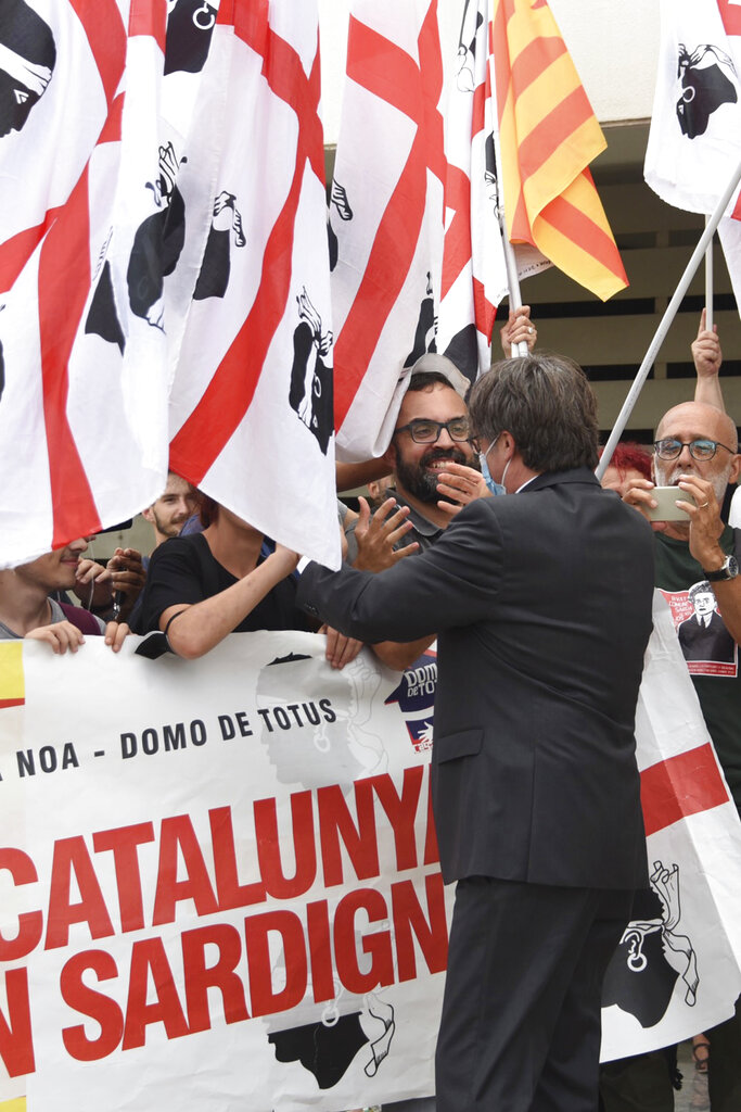 Catalan leader Carles Puigdemont greets supporters outside Sassari court, Italy, Monday, Oct. 4, 2021. Catalonia's former separatist leader Carles Puigdemont walked out of a Sardinian courthouse Monday after a judge delayed a decision on Spain's extradition request and said he was free to travel.  (AP Photo/Gloria Calvi)