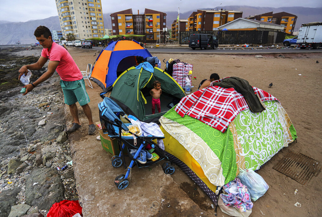 A family of Venezuelan migrants set up camp along a beach after they and other migrants were evicted by police from Brazil Square where they were living in tents, in Iquique, Chile, Friday, Sept. 24, 2021. Hundreds of migrants from Venezuela and Colombia have been living in the historic sector of the city for over a year. (AP Photo/Ignacio Munoz)