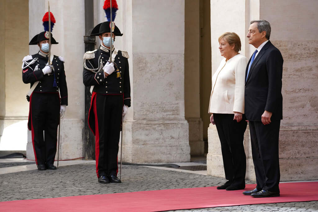 Italian Premier Mario Draghi, right, and German Chancellor Angela Merkel review the honor guard at Palazzo Chigi Premier office, in Rome, Thursday, Oct. 7, 2021. (AP Photo/Andrew Medichini)