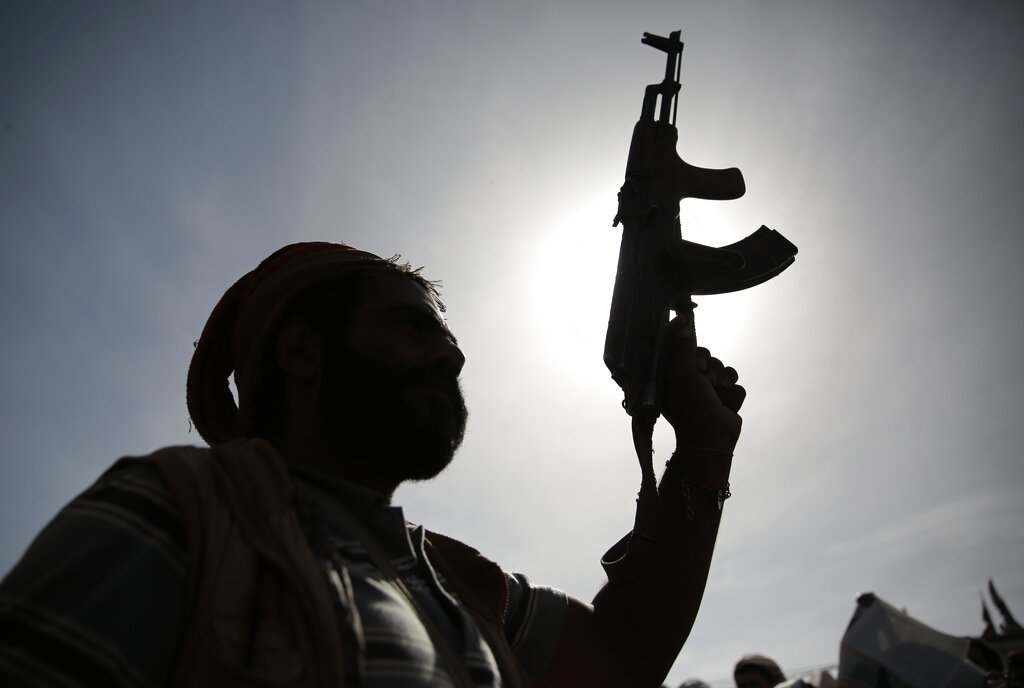 A silhouette of a Houthi supporter holds his weapon during a rally marking six years for a Saudi-led coalition in Sanaa, Yemen, Friday, March 26, 2021. A fuel tank at an oil facility in Saudi Arabia caught fire after being struck in an attack by Yemen's Houthi rebels, officials said Friday, an attack that came on the sixth anniversary of the kingdom's entry into Yemen's yearslong civil war. (AP Photo/Hani Mohammed)