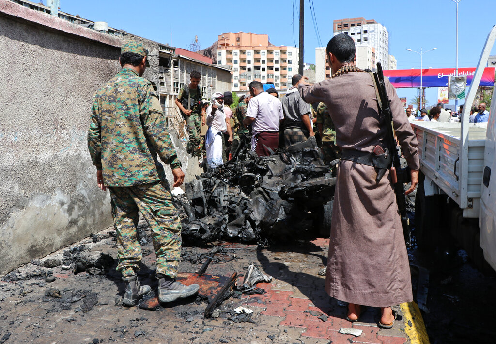 Security personnel a vehiclestand amid the wreckage of a vehicle at the site of a deadly car bomb attack that targeted two senior government officials, who survived, security officials said, in the port city of Aden, Yemen, Sunday, Oct. 10, 2021. Aden has been the seat of the internationally recognized government of President Abed Rabbo Mansour Hadi since the Iranian-backed Houthi rebels took over the capital, Sanaa, triggering Yemen’s civil war. (AP Photo/Wael Qubady)