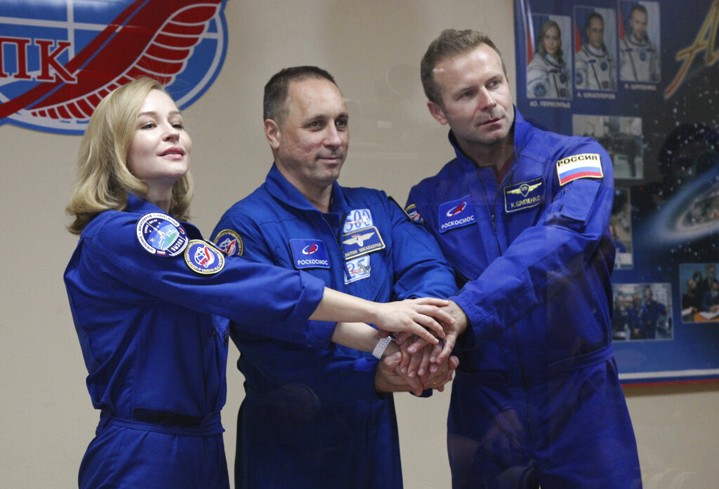 In this handout photo released by Roscosmos, actress Yulia Peresild, left, director Klim Shipenko, right, and cosmonaut Anton Shkaplerov, members of the prime crew of Soyuz MS-19 spaceship pose after a news conference at the Russian launch facility in the Baikonur Cosmodrome, Kazakhstan, Monday, Oct. 4, 2021. In a historic first, Russia is set to launch an actress and a film director to space to make a feature film in orbit. Actress Yulia Peresild and director Klim Shipenko are set to blast off Tuesday for the International Space Station in a Russian Soyuz spacecraft together with Anton Shkaplerov, a veteran of three space missions.(Roscosmos Space Agency via AP)