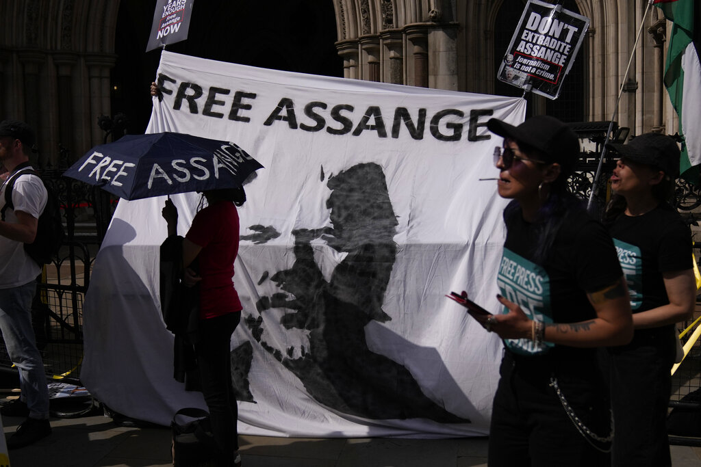 Supporters of WikiLeaks founder Julian Assange stand in front of a banner bearing an image of him, during the first hearing in the Julian Assange extradition appeal, at the High Court in London, Wednesday, Aug. 11, 2021. Lawyers acting on behalf of the U.S. government on Wednesday challenged a British judge's decision to block the extradition of WikiLeaks founder Julian Assange to face espionage charges in the United States, arguing that assessments of Assange's mental health should be reviewed. (AP Photo/Matt Dunham)