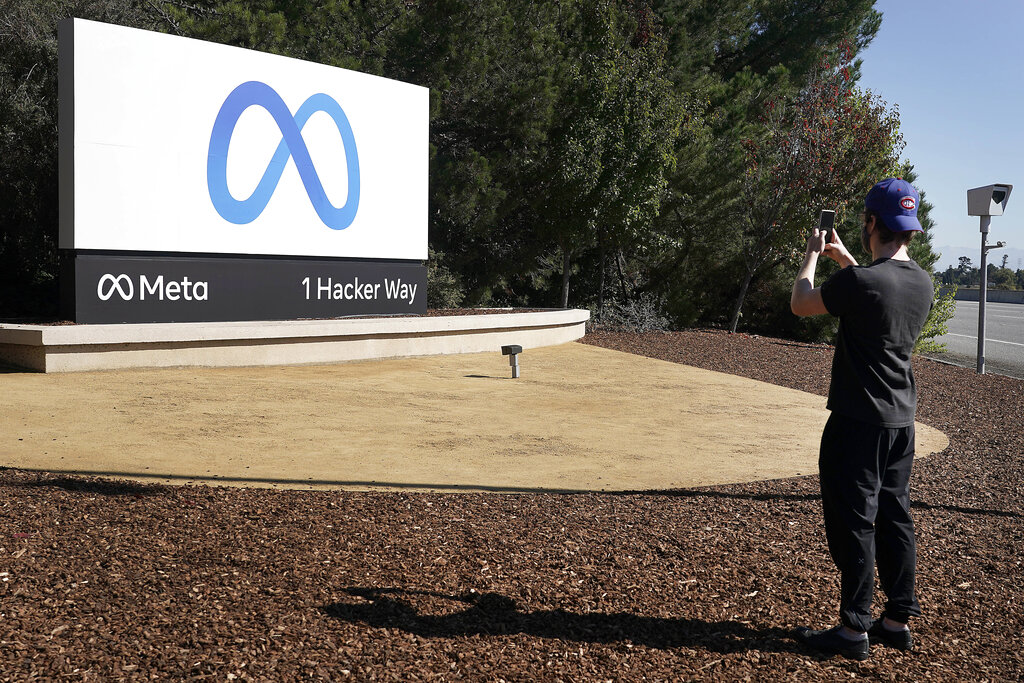 Facebook employee take a photo in front of new Meta Platforms Inc. sign outside the company headquarters in Menlo Park, Calif., Thursday, Oct. 28, 2021. An embattled Facebook Inc. is changing its name to Meta Platforms Inc., or Meta for short, to reflect what CEO Mark Zuckerberg says is its commitment to developing the new surround-yourself technology known as the “metaverse.” But the social network itself will still be called Facebook.(AP Photo/Tony Avelar)