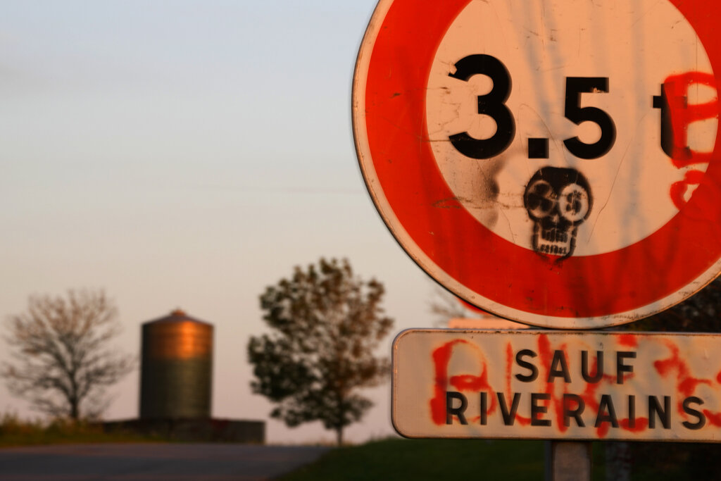 A road sign is painted with a mask with nuclear logos next to an underground laboratory run by French radioactive waste management agency Andra, in Bure, eastern France, Thursday, Oct. 28, 2021. Nuclear power is a central sticking point as negotiators plot out the world’s future energy strategy at the climate talks in Glasgow, Scotland. France is laying the groundwork for a permanent, deep-earth repository beneath corn and wheat fields outside the nearby stone-house hamlet of Bure. (AP Photo/Francois Mori)