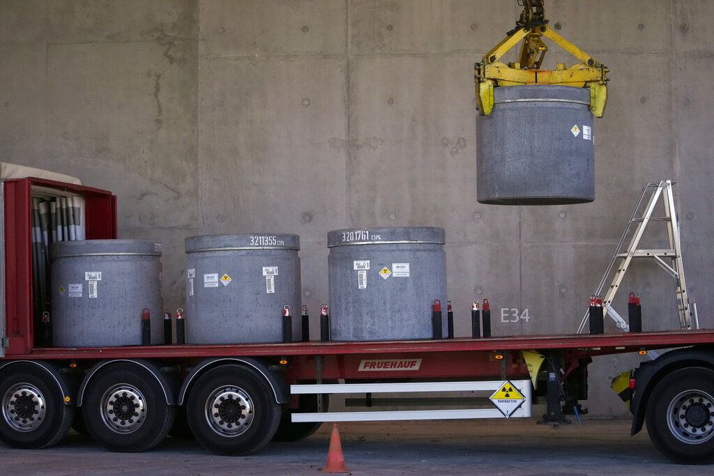 Radioactive waste storage is lifted from a truck in a concrete-sealed warehouse in the Aube region of eastern France managed by French radioactive waste management agency Andra, in Soulaines-Dhuys, Friday, Oct. 29, 2021. Deep in a French forest of oaks, birches and pines, a steady stream of trucks carries a silent reminder of nuclear energy’s often invisible cost: canisters of radioactive waste, heading into storage for the next 300 years. (AP Photo/Francois Mori)