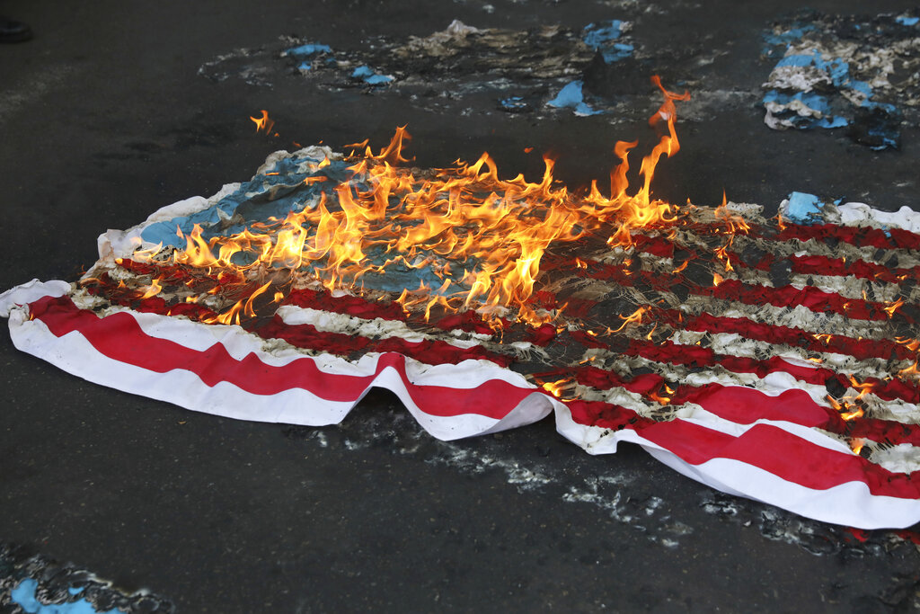 A mock U.S. flag is set on fire by demonstrators during a rally in front of the former U.S. Embassy commemorating the anniversary of its 1979 seizure in Tehran, Iran, Thursday, Nov. 4, 2021. The embassy takeover triggered a 444-day hostage crisis and break in diplomatic relations that continues to this day. (AP Photo/Vahid Salemi)
