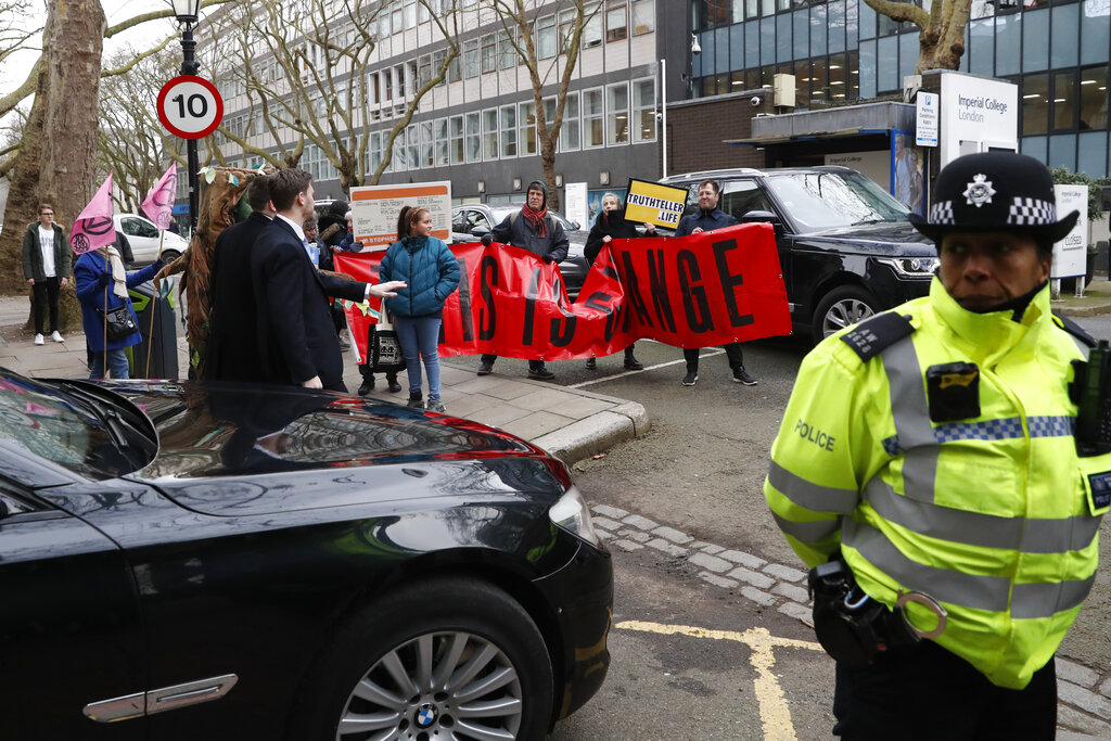Protesters stand in the road as a police car in a convoy for the Italian Prime Minister Giuseppe Conte passes by, in London, Tuesday, Feb. 4, 2020. Conte is in London to attend the launch of the next UN climate conference COP26, which will be held in Glasgow, Scotland in November. Conte was not in the convoy at the time. (AP Photo/Alastair Grant)