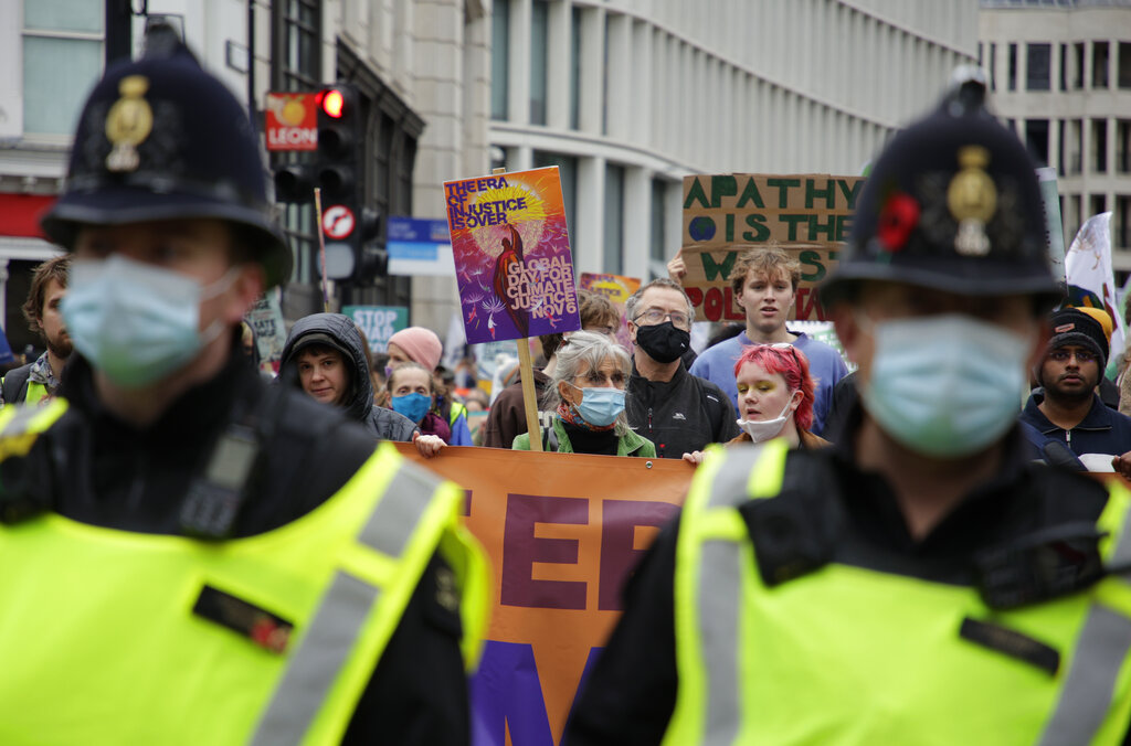 Police officers accompany climate activists as they take part in a protest through the streets of London, Saturday, Nov. 6, 2021. Many people across the world are taking part in protests as the first week of the COP26, UN Climate Summit in Glasgow comes to an end. (AP Photo/David Cliff)