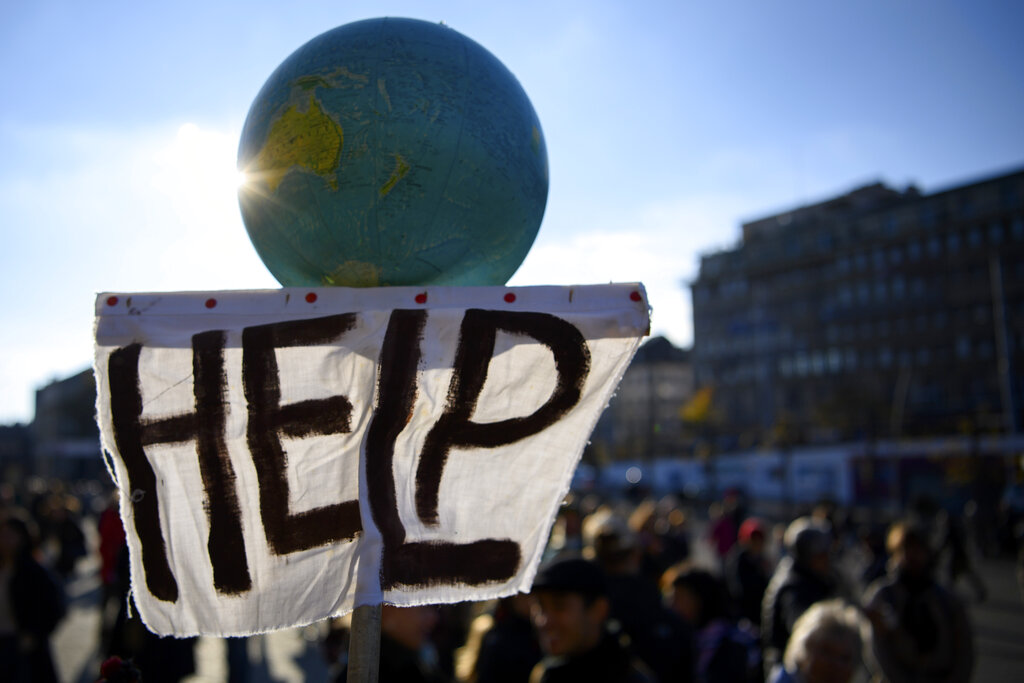 People hold a globe with a message, during a climate demonstration, in Lausanne, Switzerland, Saturday, Nov. 6, 2021.  Many people across the world are taking part in protests as the first week of the COP26, UN Climate Summit in Glasgow comes to an end.  (Laurent Gillieron/Keystone via AP)