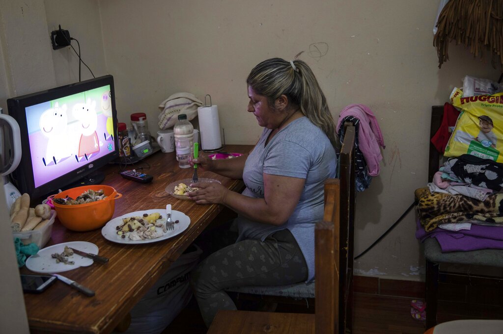 Graciela Colman, 46, single mother of 3 daughters, eats a lunch donated by the El Alfarero popular dining room, inside her home in Buenos Aires, Argentina, Thursday, Nov. 11, 2021. In the midst of a severe economic crisis, legislative elections are scheduled for Nov. 14. (AP Photo/Rodrigo Abd)