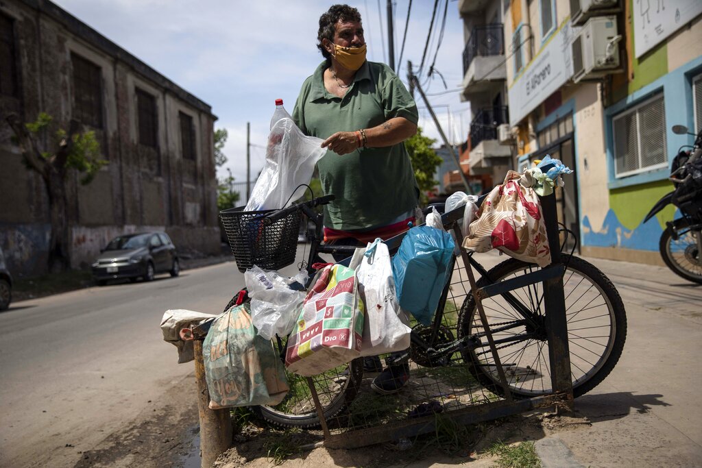 Unemployed since the beginning of the pandemic, Guillermo Fransca, 56, arrives where the neighbors place their bags of containers to collect free food while they wait in a line at the El Alfarero popular dining room in Buenos Aires, Argentina, Tuesday, Nov. 9, 2021. In the midst of a severe economic crisis, legislative elections are scheduled for Sunday. (AP Photo/Rodrigo Abd)