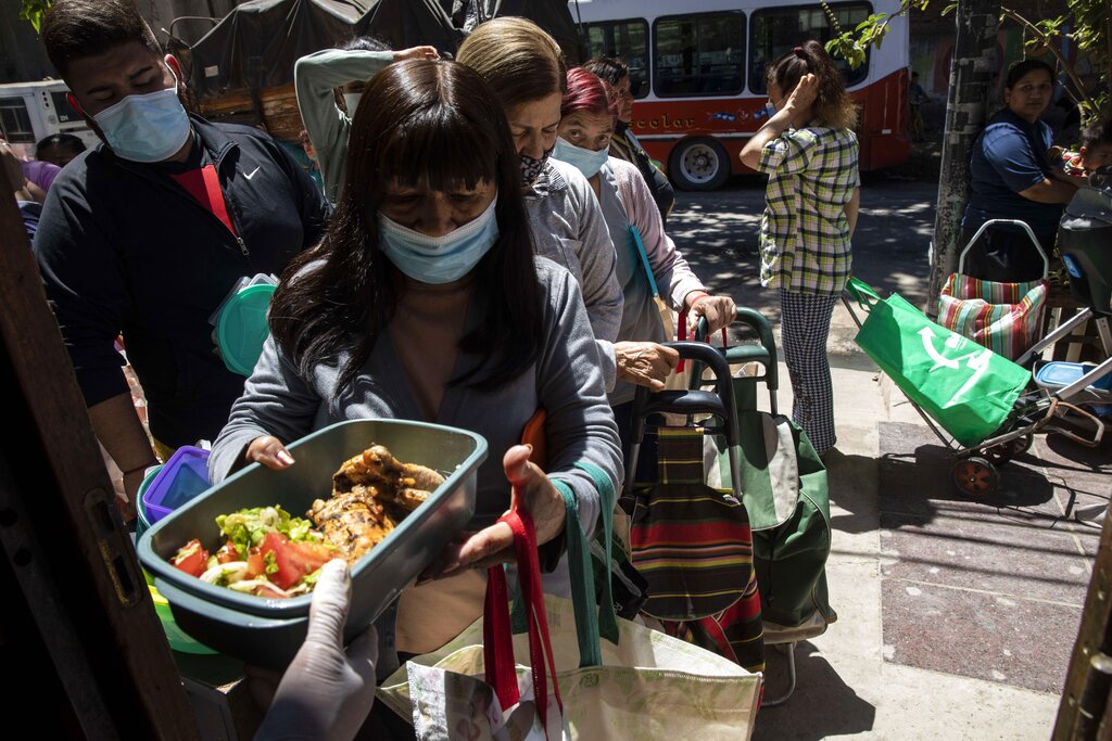 Residents receive free food outside the El Mision Padre Pepe popular dining room, in Buenos Aires, Argentina, Thursday, Nov.11, 2021. In the midst of a severe economic crisis, legislative elections are scheduled for this Sunday. (AP Photo/Rodrigo Abd)