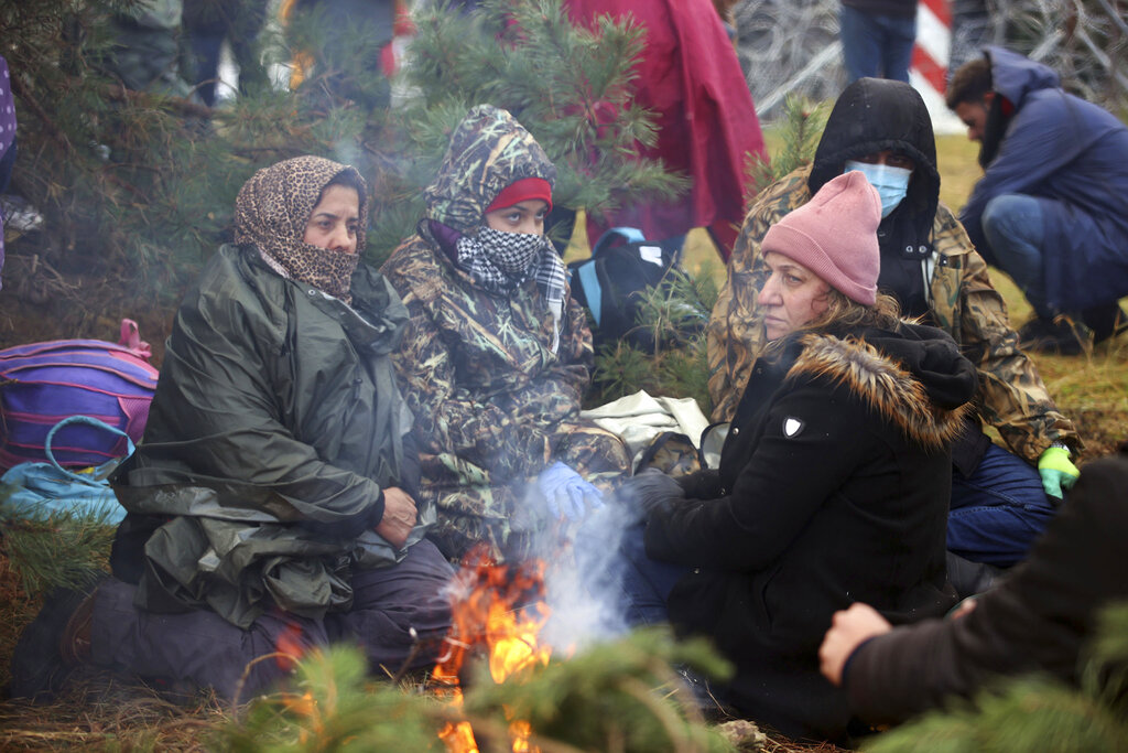 Migrants from the Middle East and elsewhere warmup at the fire gathering at the Belarus-Poland border near Grodno, Belarus, Monday, Nov. 8, 2021. Poland increased security at its border with Belarus, on the European Union's eastern border, after a large group of migrants in Belarus appeared to be congregating at a crossing point, officials said Monday. The development appeared to signal an escalation of a crisis that has being going on for months in which the autocratic regime of Belarus has encouraged migrants from the Middle East and elsewhere to illegally enter the European Union, at first through Lithuania and Latvia and now primarily through Poland. (Leonid Shcheglov/BelTA via AP)