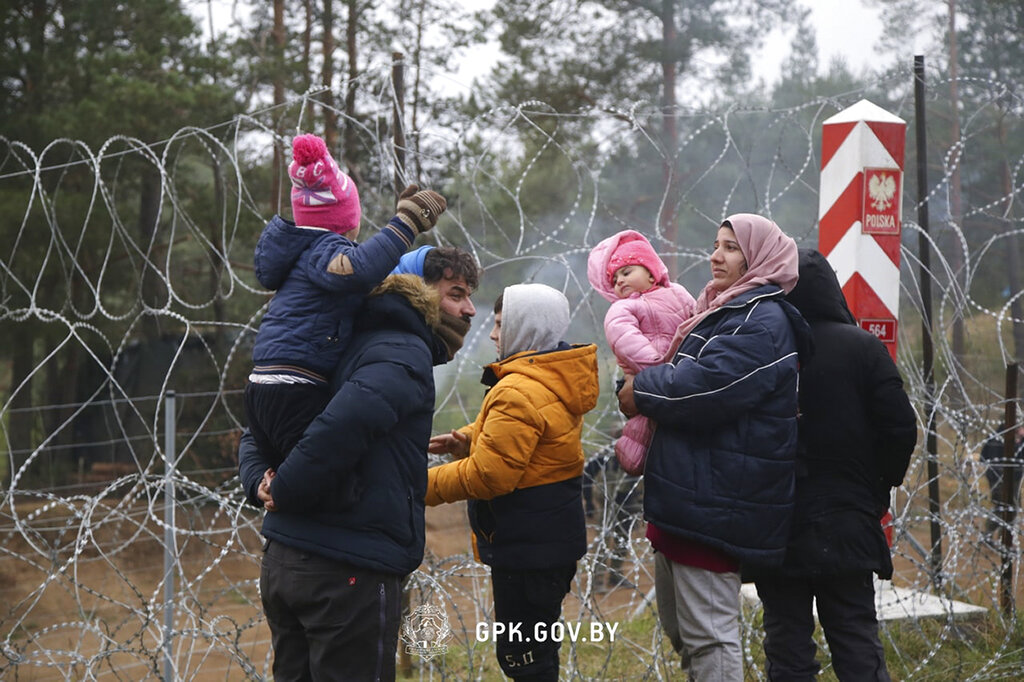 In this handout photo released by State Border Committee of the Republic of Belarus on Wednesday, Nov. 10, 2021, Migrants from the Middle East and elsewhere stand near near the barbed wire gathering at the Belarus-Poland border near Grodno, Belarus. Thousands of migrants have flocked to Belarus' border with Poland, hoping to get to Western Europe, and many of them are now stranded at the frontier, setting up makeshift camps as Polish security forces watch them from behind a razor-wire fence and prevent them from entering the country. (State Border Committee of the Republic of Belarus via AP)