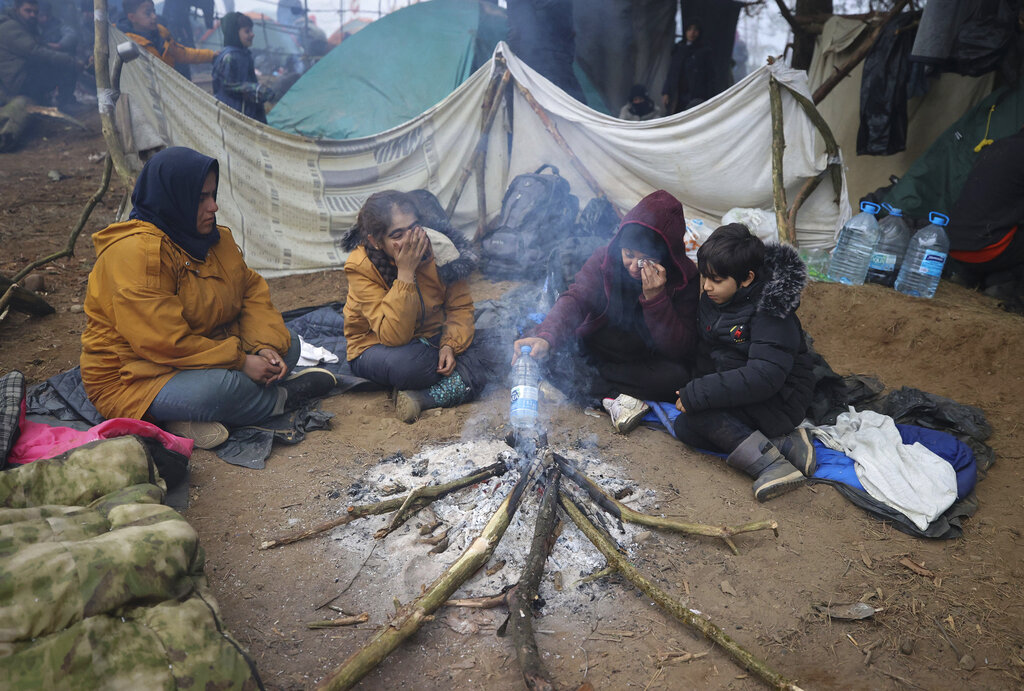 Migrants from the Middle East and elsewhere warm up at the fire gathering at the Belarus-Poland border near Grodno, Belarus, Thursday, Nov. 11, 2021. The European Union has accused Belarus' authoritarian President Alexander Lukashenko of encouraging illegal border crossings as a 