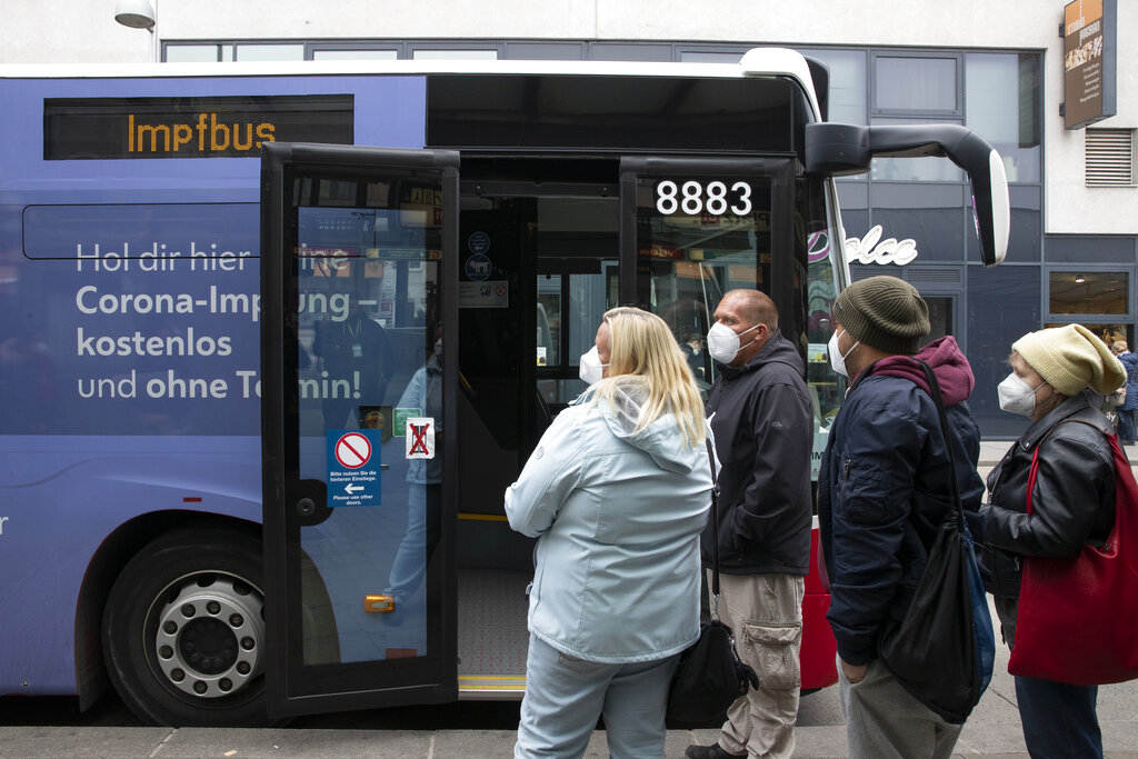 People wait in line to get vaccinated against the COVID-19 virus in a public bus, that drives around the city and offers the COVID-19 vaccination without appointments and for free in Vienna, Austria, Monday, Nov. 15, 2021. (AP Photo/Lisa Leutner)